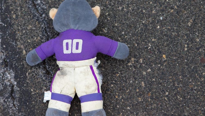 Eagles fans celebrate as people drive their cars over a stuffed vikings animal.