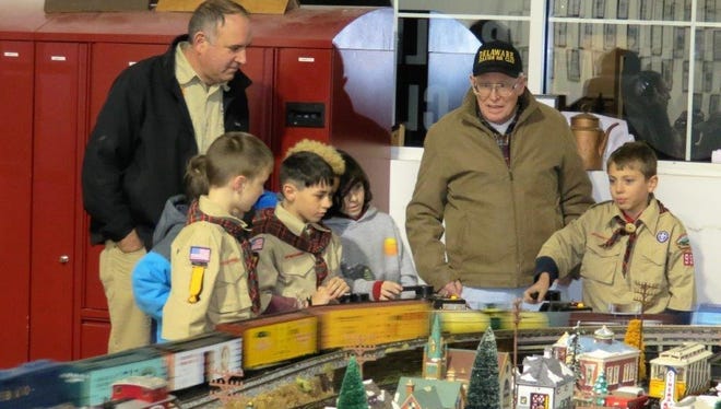 A visiting Scout tries out the controls of a model train display at the club as club members and fellow Scouts look on.