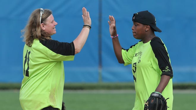Olympic gold medalist and Special Olympics coach Dionna Harris (left) shares a high-five with Ka'Neisha Mickens of the team of students from Networks School for Employability Skills during the Special Olympics softball competition at the University of Delaware Saturday.