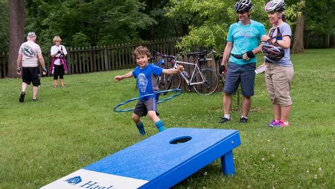 Dominic Marchesi (age 7) hula hoops during a break in the rain at the Bike & Hike event at Hagley Museum in Wilmington while his parents, Louis and Stephanie Marchesi of New London, Pa., look on.