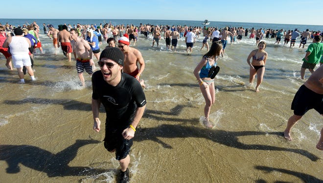 Thousands of chilled swimmers emerge from the water after diving into the Atlantic during the annual AGH Penguin Swim Thursday afternoon in Ocean City.