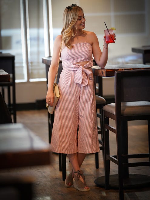 Skyler Bouchard wears a Pink Turtle strapless red and white pinstripe pantsuit with a cutout and tie in the front and flared cropped pants;with Seychelles tan suede and straw wedges.