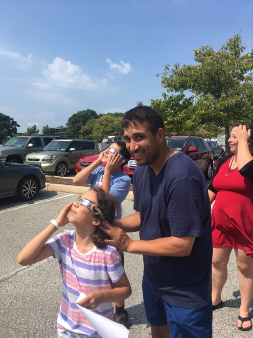 David Desantos holds the eclipse glasses for his 8-year-old daughter, Sarah at the Worcester County Library in Ocean City on Monday, Aug. 21. When Desantos was 8, he saw his first eclipse.