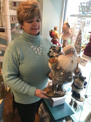 Linda Abrams, co-owner of Sea Finds, shows off a nautical Santa statue. The store features gifts and home decor items primarily with a coastal theme.