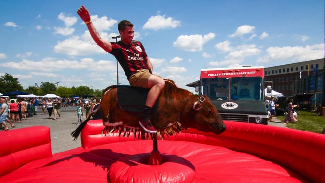 Connor Fawzi of Pennsylvania rides the mechanical bull at the inaugural Delaware Taco Festival Saturday at Frawley Stadium in Wilmington.
