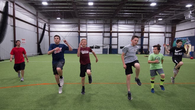 Jeff Simpson, left, owner and head strength coach with Sports Specific Training, works with a group of athletes at Slim's Sport Complex in Middletown.