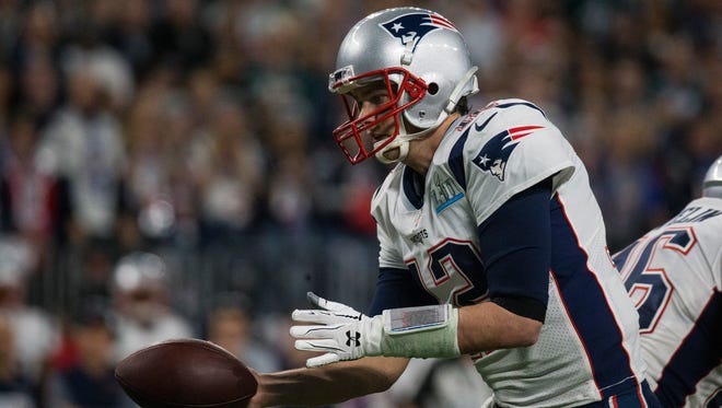 New England's Tom Brady reaches back for a handoff Sunday at US Bank Stadium.