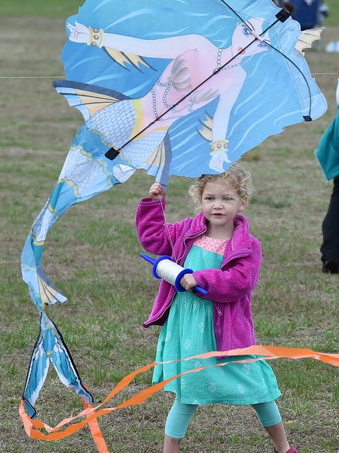 3 year old Violet Howard from Seaford works to get her kite airborne as despite cloudy and rainy weather, the 48th Annual Kite Festival was held on Friday March 25th at Cape Henlopen State Park near Lewes with a good crowd on hand flying all kinds of kites and creations.