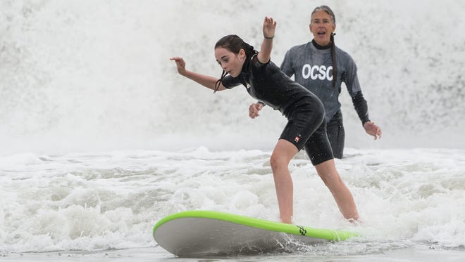 Madison Pusey balances herself on a surf board while instructor Elisa Behnk watches in Ocean City on Sunday, Oct. 15, 2017.