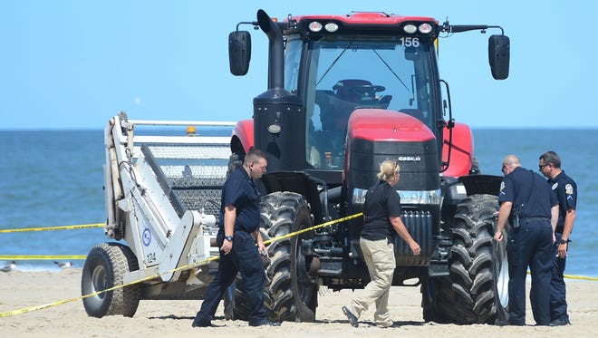 Ocean City Police and Forensics Units look at one of the beach tractors tires near where an unidentified body was found this morning around the 2nd Street beach in Ocean City, Md. on Monday, July 31, 2017.