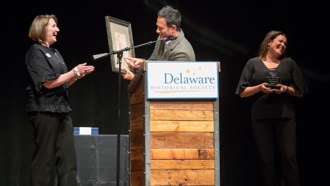 Delaware Historical Society Chair Peg Laird, left, awards the 2018 Delaware History Makers award to Dogfish Head Craft Brewery, Inc. founders Sam Calagione, center, and Mariah Calagione Thursday night at the Queen in Wilmington.