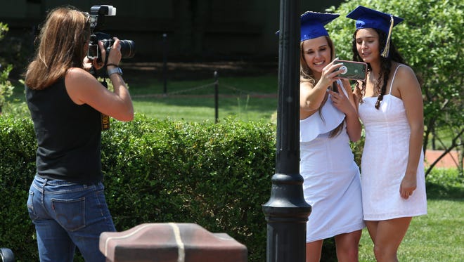 University of Delaware seniors Emma Charlton of Berwyn, Pa., and Alina Libowitz of Longmeadow, Mass. (right)  take part in a bucket list experience - photos and wading in the fountain on the Green as  Emma's mother, Lynn photographs them Wednesday.