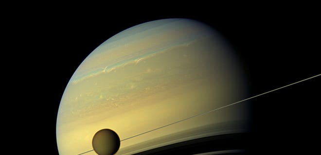 A moon appears before a planet undergoing seasonal changes in this natural color view of Titan and Saturn from NASA's Cassini spacecraft, released in August 2012.