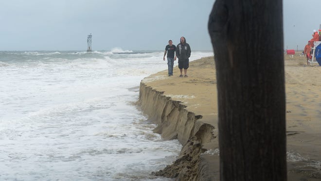 Two gentlemen walk along the Ocean City beach where a summer nor'easter passing through has over the last few hours been causing beach erosion.
