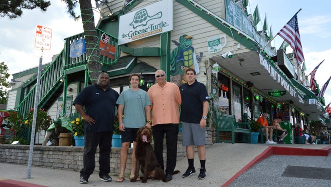 The current faces of the original Greene Turtle on 116th Street in Ocean City — operations manager Shawn Sturgis, Stephen Pappas, Greene Turtle founder Steve Pappas, Jason Pappas, and Leo the 10-month-old labradoodle.