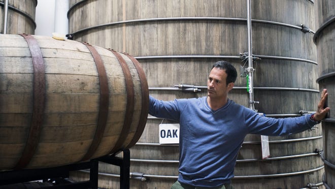 Dogfish Head founder Sam Calagione checks on barrels of aging beer at the Milton brewery.
