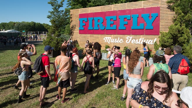 Festival goers pose for photos next to the Firefly Music Festival sign.