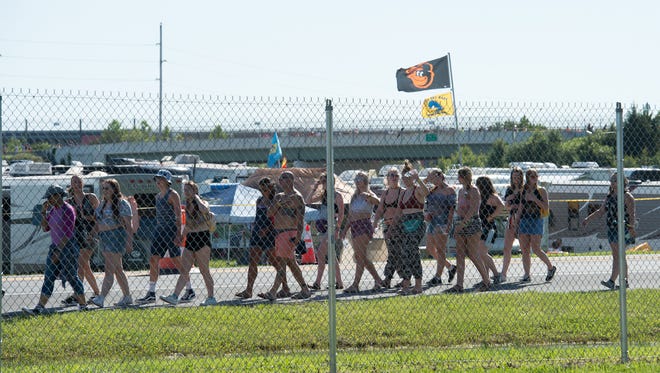 Festival goers pass walk toward the gates on the opening day of the Firefly Music Festival in Dover.