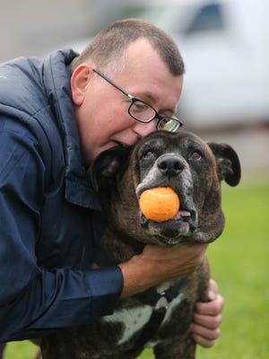 Pete Buchmann, 54, gives his 9 year-old dog Buster, a hug while plain with him outside of Faithful Friends.