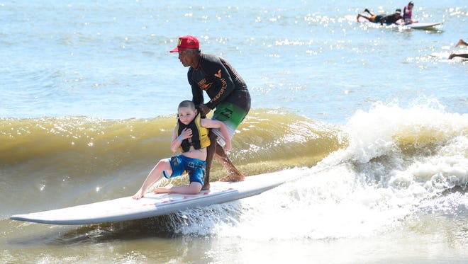 Tristan Dunn, 6, Shrewsbury, Pa. is helped by one of the volunteers with the Surfers Healing tour catch a wave  in Ocean City on August 17, 2016.