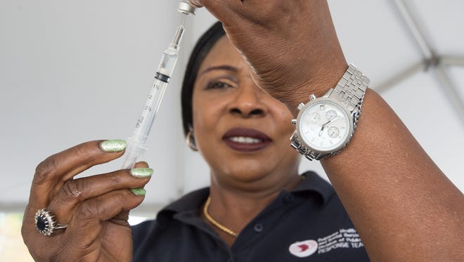 Helen Madukwe, a registered nurse with the Division of Public Health, prepares a flu vaccination at their drive-thru flu vaccination clinic at the DelDOT Administration Building in Dover.