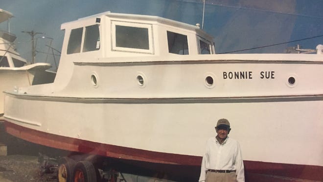 Captain Bobby Turner of Wachapreague, Virginia stands beside his boat, the Bonnie Sue, in this undated family photograph. Turner, 86, has used the boat for 70 years. He and his father completed building the boat in 1947, after Tom Young built the hull.