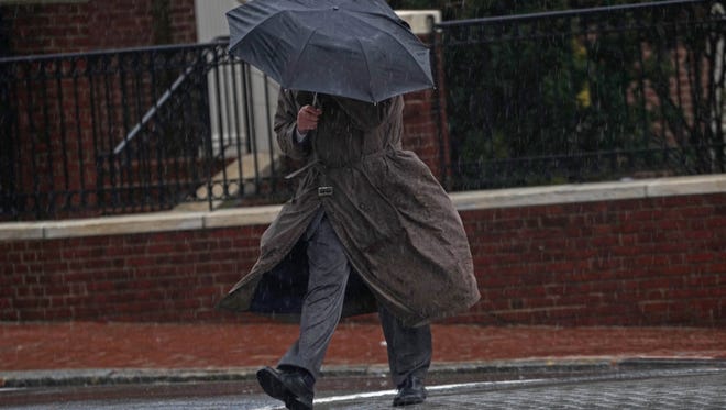 A pedestrian walks across 11th Street near Rodney Square in the torrential rain and wind on Monday afternoon.