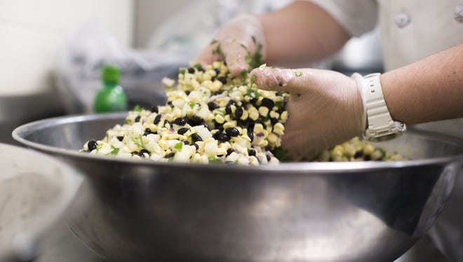 SoDel Concepts corporate chef Ronnie Burkle tosses a jicama-based black bean salad at Indian River High School.