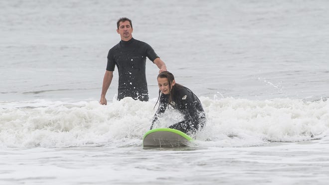 Instructor Mark Vastine watches as Ellie Johnson rides a wave in Ocean City on Sunday, Oct. 15, 2017.