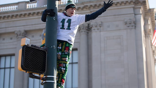 A fan climbs a light pole during the Super Bowl LII parade on February 8, 2018 in Philadelphia, Pennsylvania.