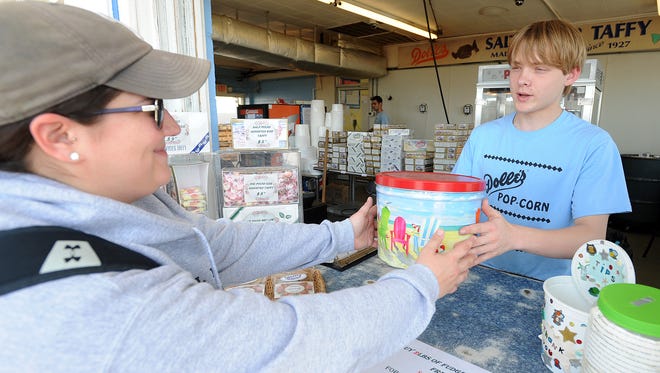 Thomas Ibach Jr. of Dolle's Candyland at Rehoboth Avenue and the Boardwalk sells customer Jen Gromis a can of caramel popcorn the Friday before Memorial Day.