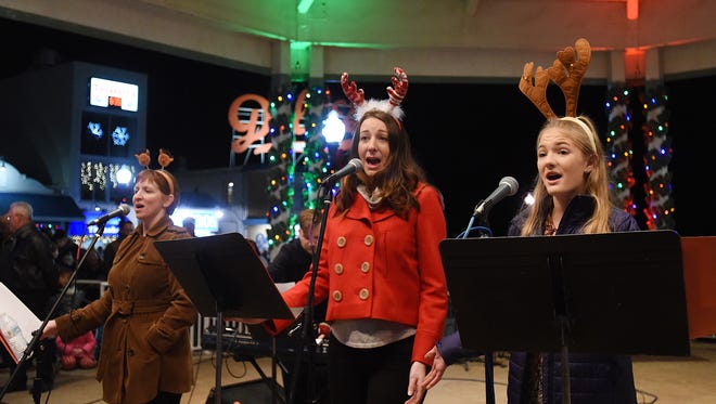 Nancy Curry, Kelsey Murphy and Grace Morris, all from Clear Space Theater Group, lead the crowd in a sing-along at the annual Rehoboth Beach Christmas tree lighting ceremony at the Bandstand on Friday, Nov. 24, 2017.