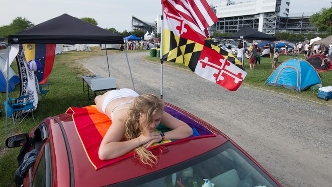 Katie Usary of Boonsboro, Md., lays on top of her car in the camping area at the Firefly Music Festival in Dover.