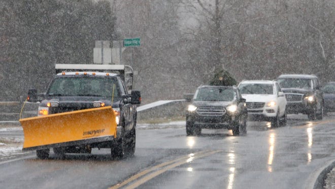 A plow-equipped pickup passes through the intersection Adams Dam Road and Thompsons Bridge Road as snow begins to drape the area Saturday morning.