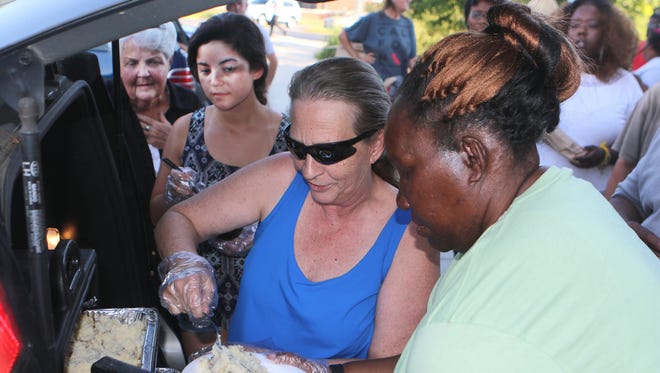 Sue Harris (center), director of Port Hope Delaware, Inc., serves Dover's homeless a hot meal out of the back of her car every Tuesday and Saturday at the Dover Public Library. The food is donated by Cheddar's Scratch Kitchen in Camden. Helping her are Becca Gasperetti (left) and Denise Daniel (right).