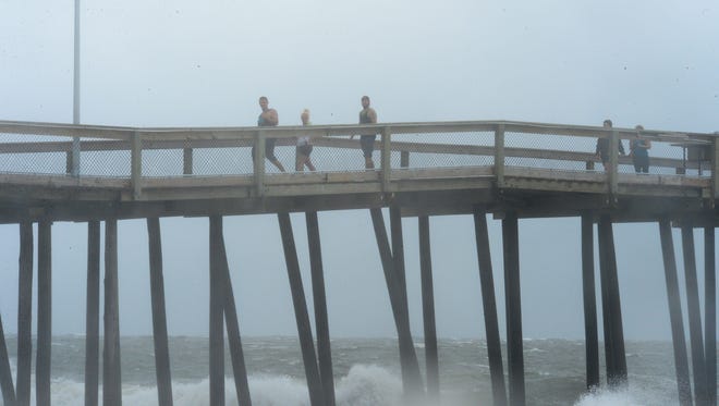 People walk out on the pier to get a better look at the waves and weather as a summer nor'easter passes through Ocean City, Md. on Saturday, July 29, 2017.