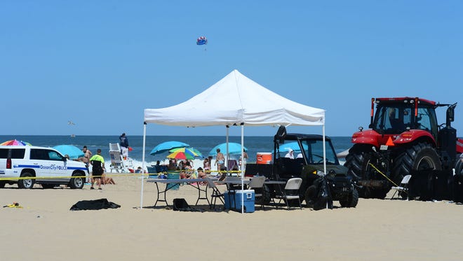 Beach goers sit outside the police line area where an unidentified body was found this morning around the 2nd Street beach in Ocean City, Md. on Monday, July 31, 2017.