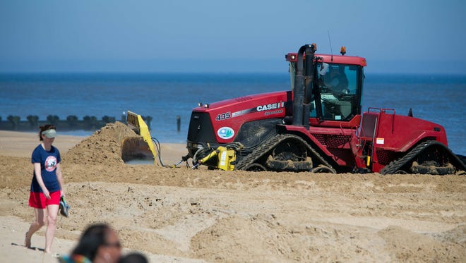 A bulldozer pushes sand at Rehoboth Beach during an unseasonably warm day on March 9. Conservation group Oceana is calling for a halt to seismic testing in the area off the Delaware coast to Florida