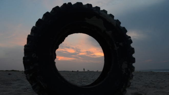 Spectators are seen through a washed up tire as they set up on the beach just before sunrise to wait for the northern herd to be led to their corral on Assateague Island, Va. on Monday morning, July 25, 2016. The 91st Annual Chincoteague Pony Swim is Wednesday.