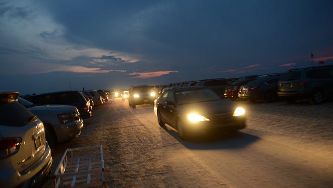 Cars fill the parking lot at Assateague beach at sunrise as spectators prepare to watch the northern herd of Chincoteague Ponies as they are led down the beach to their corral on Monday morning, July 25, 2016.