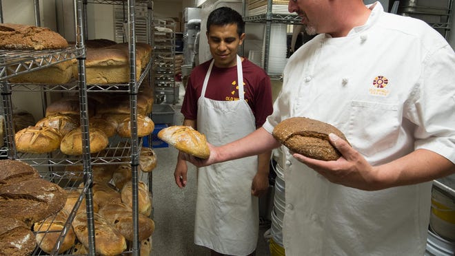 Keith Irwin, right, President of Old World Breads, and Roni Ramirez, production manager, look at freshly baked organic whole wheat sour dough with local grains and white sour dough bread at their bakery in Lewes.