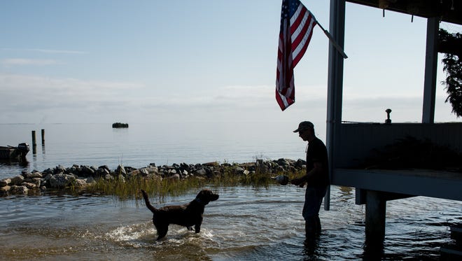 Bo Godwin, of Solomons, Maryland plays fetch with Gus in ankle high floodwater at a fishing cabin on Ape Hole Road in Crisfield on Sunday, Nov. 5, 2017.