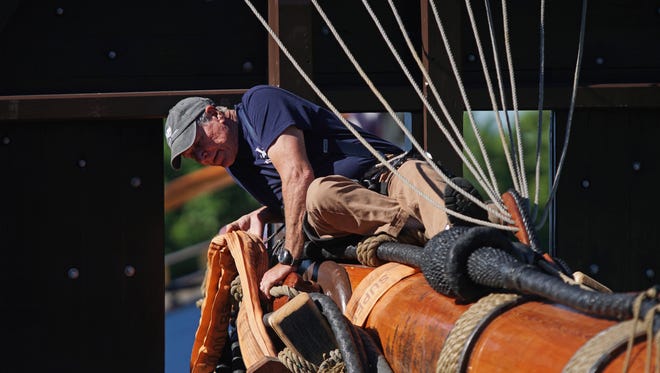 Jim Scarborough helps secure lines from a nearby crane to the fore mast on the Kalmar Nyckel that was being put back on the ship after routine maintenance.