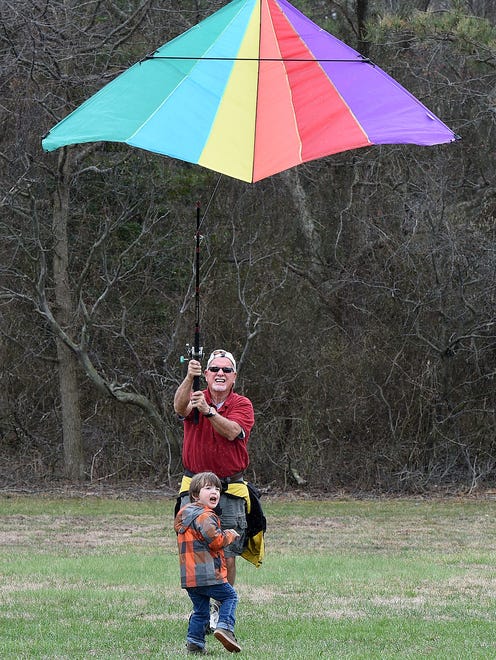 Nick Morris with grandson Theo Reister 2 from Berlin, Md. use a fishing pole to fly a kite as despite cloudy and rainy weather, the 48th Annual Kite Festival was held on Friday March 25th at Cape Henlopen State Park near Lewes with a good crowd on hand flying all kinds of kites and creations.