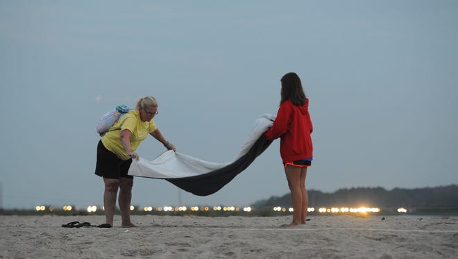 Car headlights line Beach Road as Robin Daubach and her granddaughter Abbye Daubach set up a blanket on the beach at Assateague Island, Va. to wait for Saltwater Cowboys to lead the northern herd of Chicnoteague Ponies to their corral on Monday morning, July 25, 2016. The 91st Annual Chincoteague Pony Swim is Wednesday.