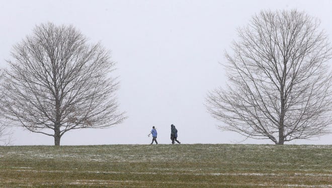 People walk through Brandywine Creek State Park as snow begins to drape the area Saturday morning.
