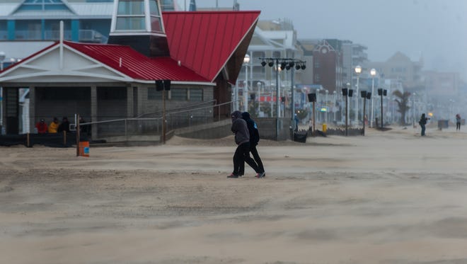 A couple races off the beach to avoid sand and rain on Friday afternoon in Ocean City.