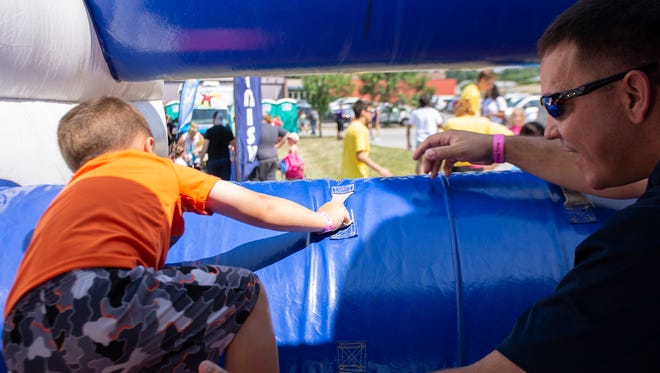 Brennan Smith, 3, and Michael Smith, YMCA Dictor, work together to go through the last obstacle course at The Great Inflatable Race in Shrewsbury, Pa. on Saturday, July 14, 2018.