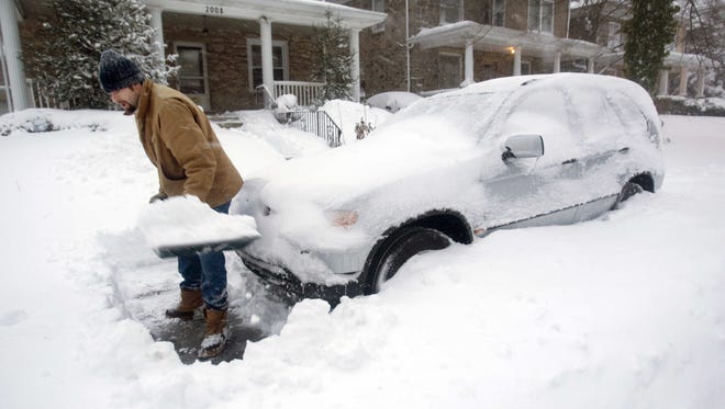 Jim Phillips clears space around his car on N. Van Buren Street to allow his wife, a doctor, go to work at St. Francis Hospital in Wilmington shortly after dawn as snow continues to fall Wilmington, Saturday, Feb. 6, 2010.
