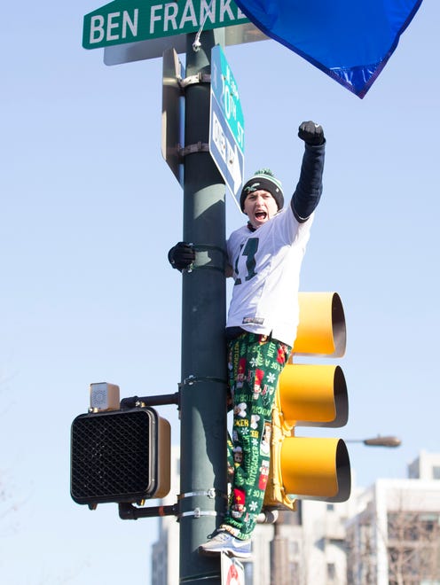 A fan climbs a light pole during the Super Bowl LII parade on February 8, 2018 in Philadelphia, Pennsylvania.
